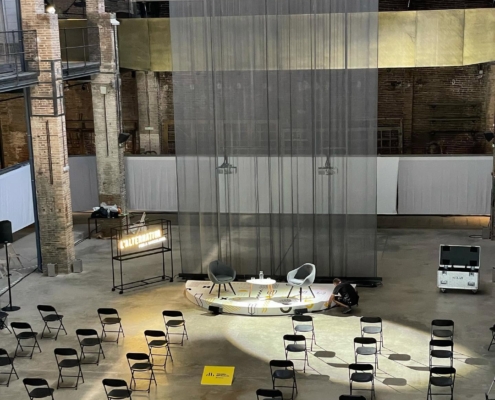 Montaje de un evento en recinto industrial: escenario, sillas y preparación técnica antes de la apertura